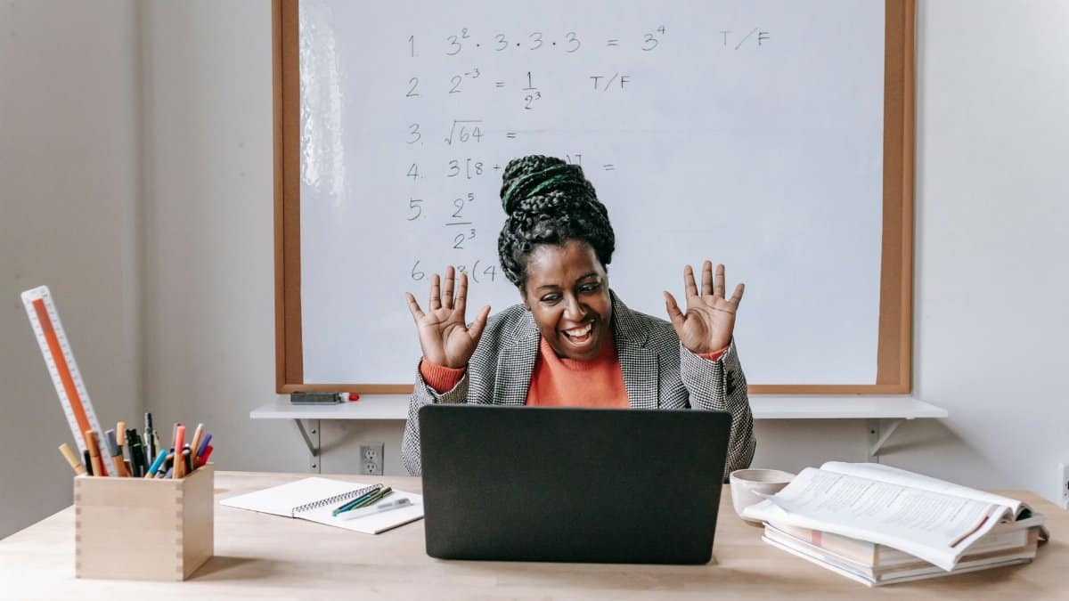Cheerful African American female teaching online lesson with netbook in modern classroom