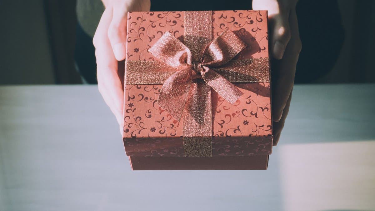 Hands presenting a beautifully wrapped gift box with a floral pattern, perfect for any celebration.