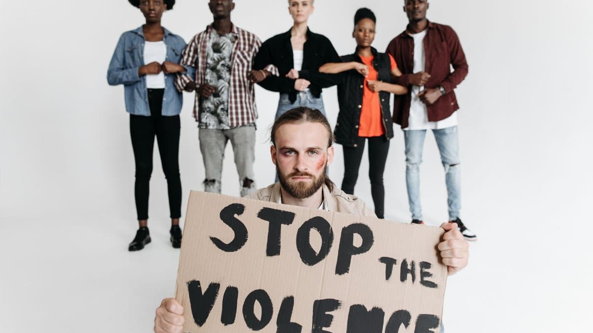 A group of people holding a cardboard sign that reads 'Stop the Violence' during a studio protest shoot.