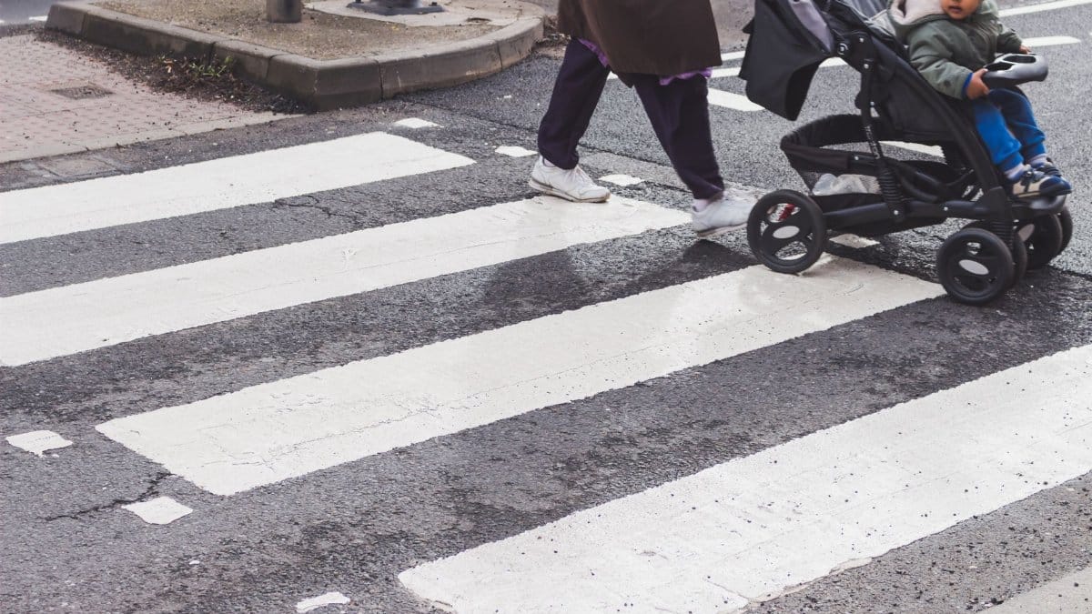 A child in a stroller crossing a zebra crossing in the city. Urban street scene focusing on pedestrian safety.