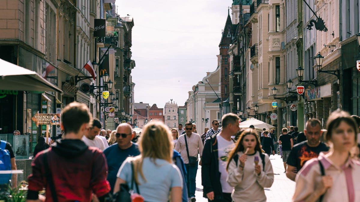 Vibrant urban street scene in Toruń, capturing people and historic architecture on a sunny day.