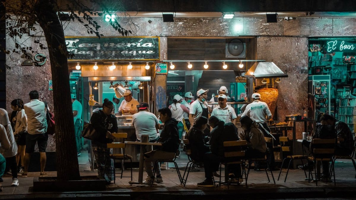 Crowded urban street restaurant at night, capturing lively city nightlife and dining.