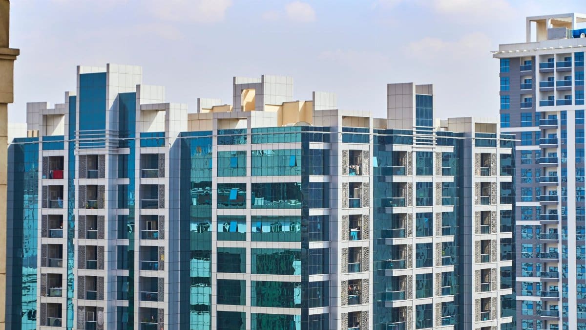 A cityscape view of modern high-rise buildings with reflective glass facades under a blue sky.