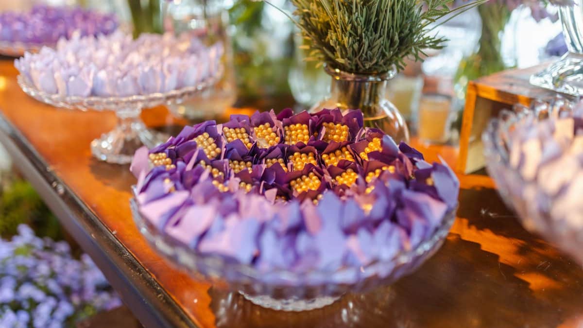 Lavish selection of wedding desserts with purple floral accents on display.