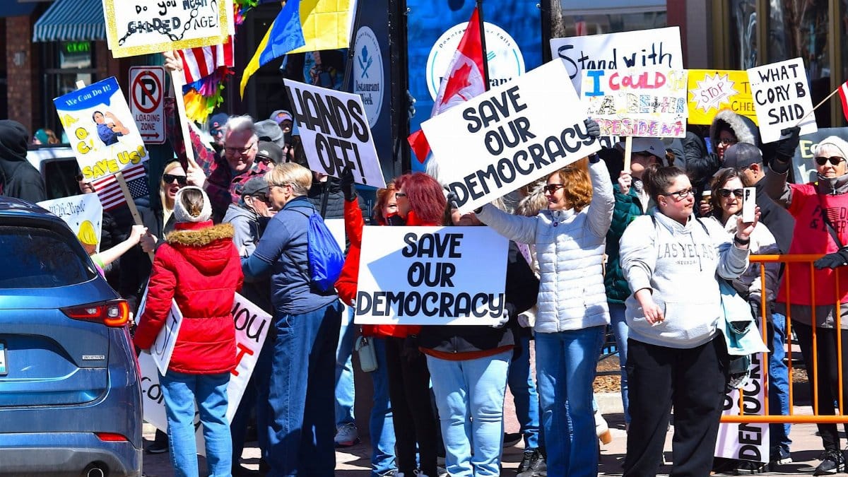 Group of people protesting for democracy in downtown Sioux Falls, holding signs for democratic rights.