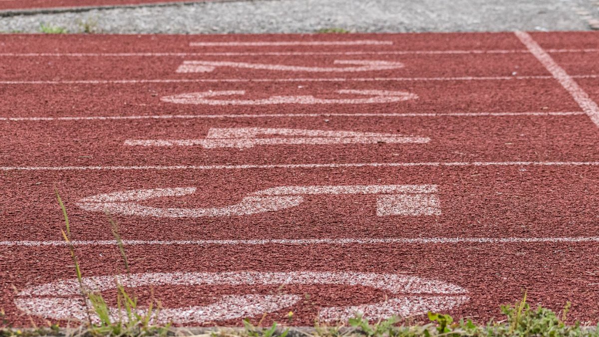Detailed view of a red running track's starting line numbers, ideal for sports themes.