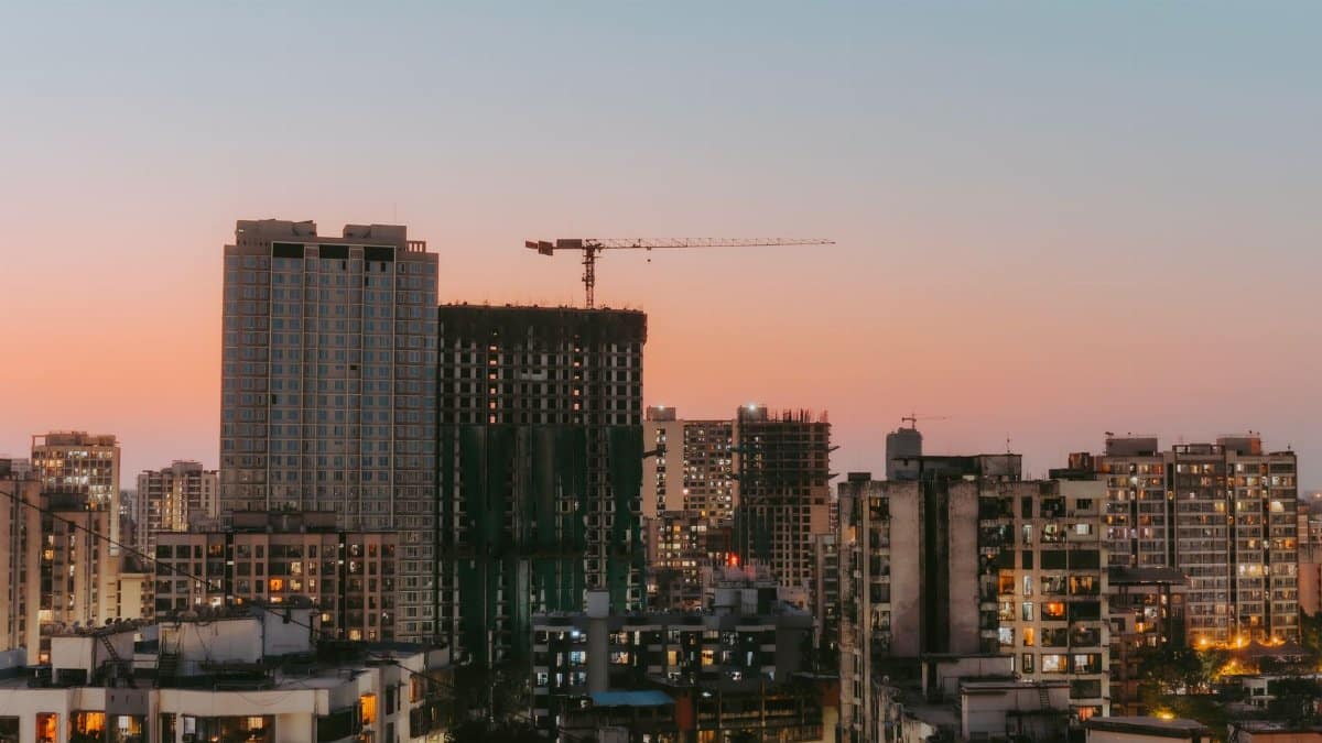 Cityscape view with buildings and a construction crane at sunset, highlighting urban development.