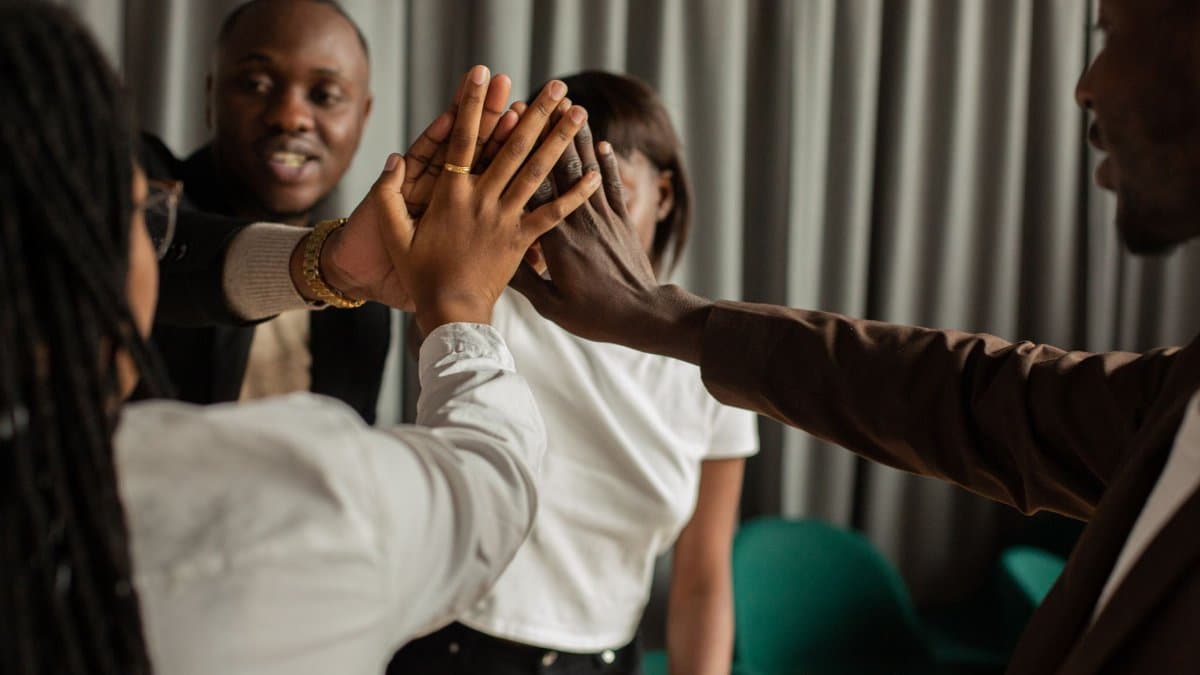 A diverse group of professionals participating in a motivational team huddle indoors.