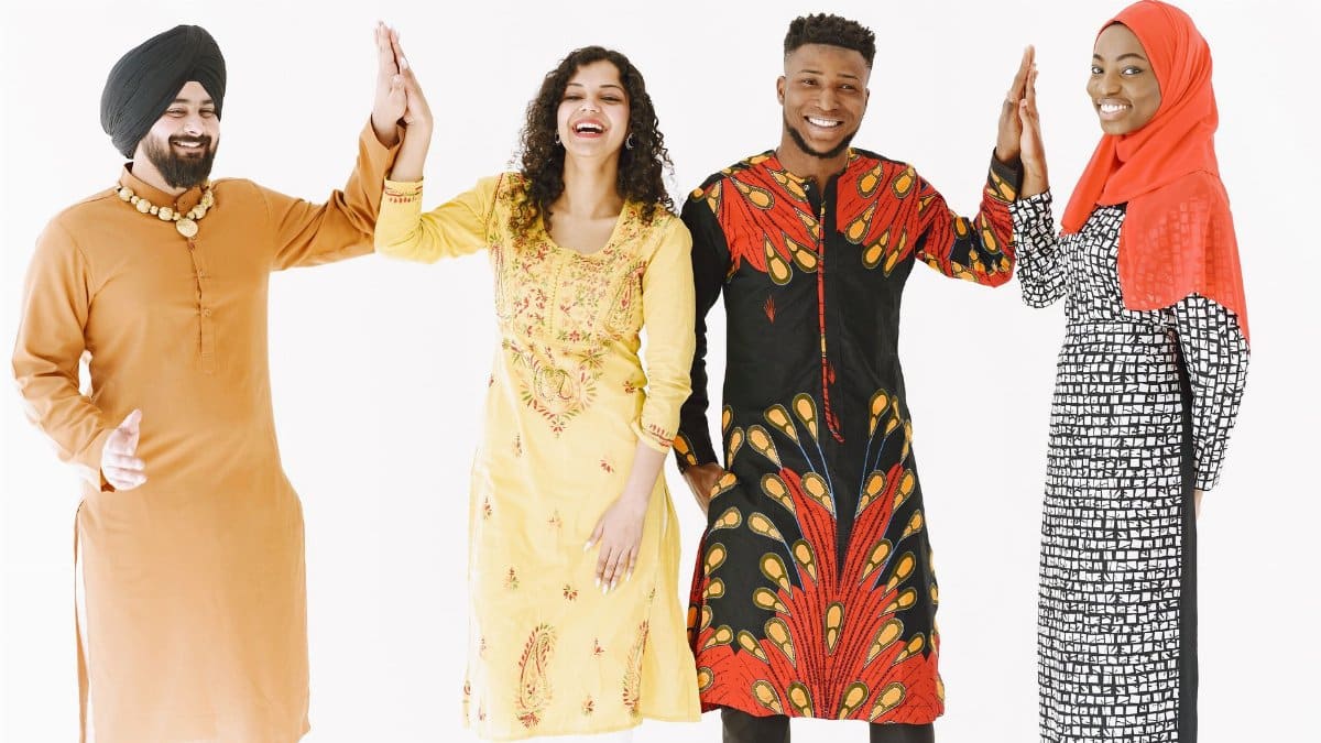 A joyful group of adults from diverse backgrounds high-fiving in traditional clothing.