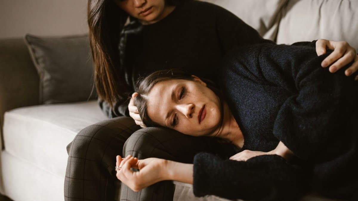 Two women on a couch, one comforting the other, depicting empathy and support.