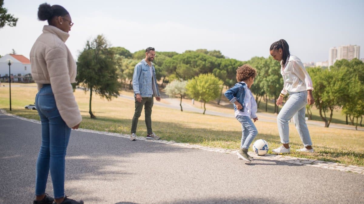A diverse family enjoys playing soccer in a sunny park in Portugal, capturing fun and bonding.