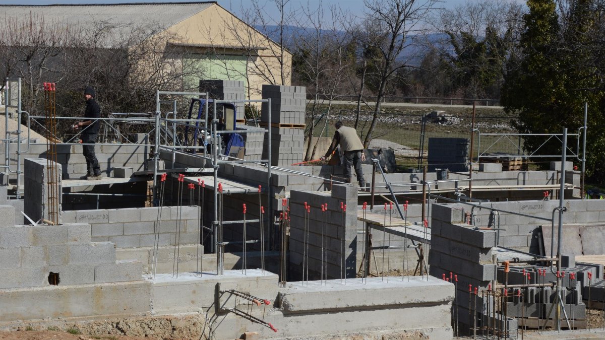 Construction workers building a concrete structure at a sunlit site.