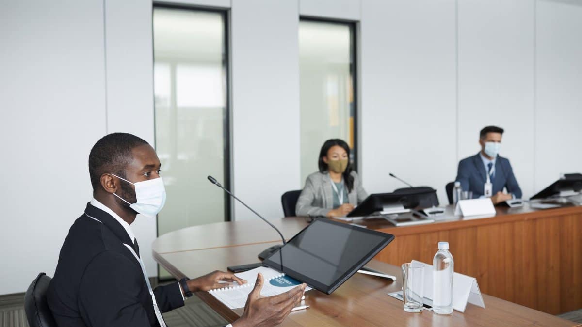 Professionals in face masks hold a business meeting in a modern conference room.