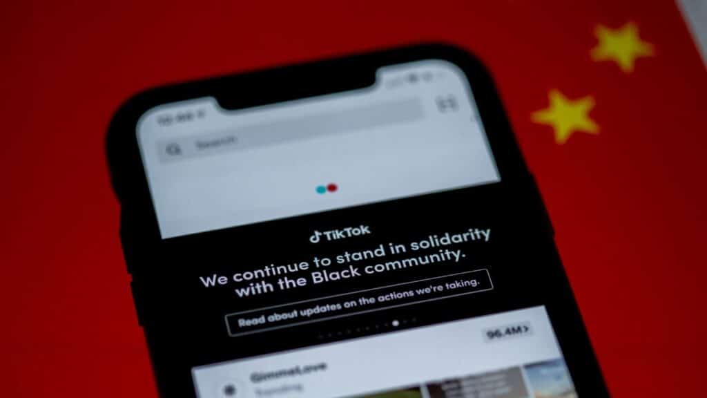 Close-up of a smartphone with TikTok app displayed against a China flag backdrop, highlighting solidarity message.