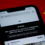Close-up of a smartphone with TikTok app displayed against a China flag backdrop, highlighting solidarity message.