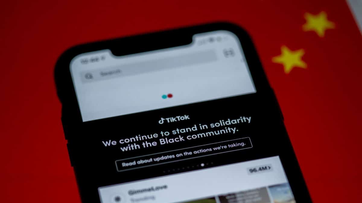 Close-up of a smartphone with TikTok app displayed against a China flag backdrop, highlighting solidarity message.