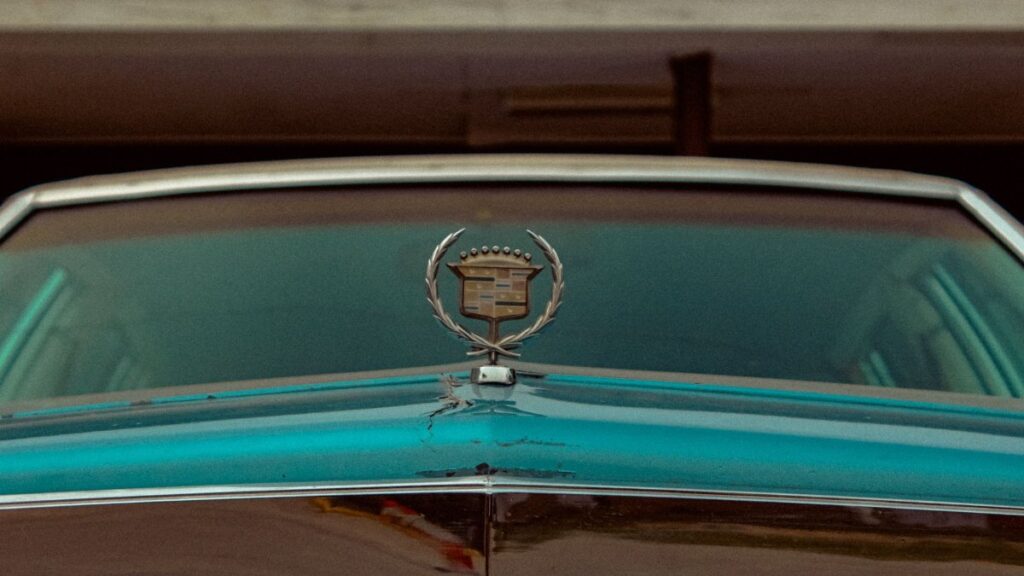 Close-up of a vintage Cadillac hood featuring its classic emblem, epitomizing nostalgia and luxury.