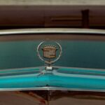Close-up of a vintage Cadillac hood featuring its classic emblem, epitomizing nostalgia and luxury.