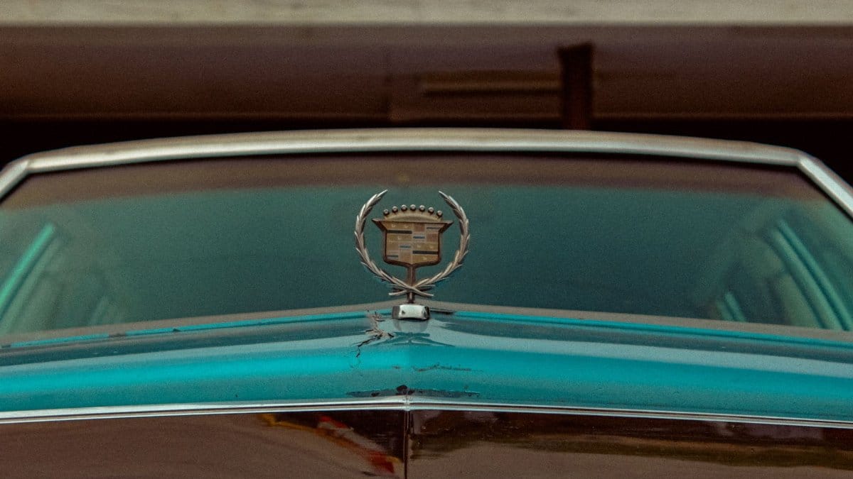 Close-up of a vintage Cadillac hood featuring its classic emblem, epitomizing nostalgia and luxury.