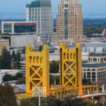 Dramatic aerial view capturing the iconic Tower Bridge and the striking skyline of Sacramento, California at day.