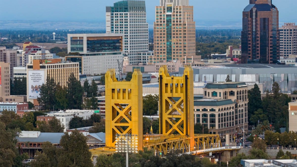 Dramatic aerial view capturing the iconic Tower Bridge and the striking skyline of Sacramento, California at day.