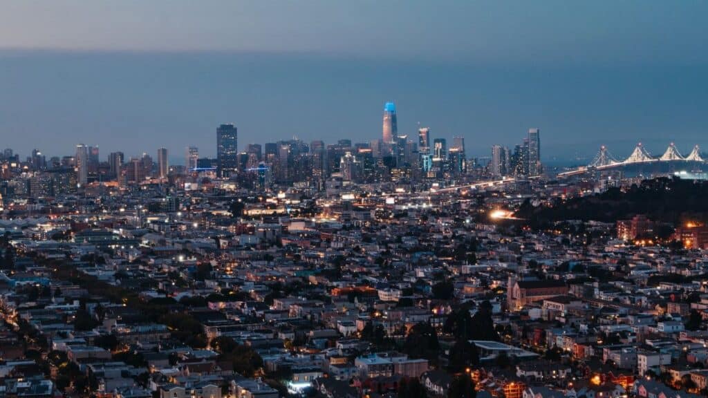 Modern illuminated skyscrapers and high rise buildings behind residential district in city at night
