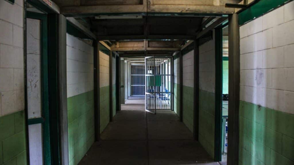 View of an empty prison corridor with open cell doors symbolizing security and isolation.