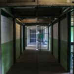 View of an empty prison corridor with open cell doors symbolizing security and isolation.