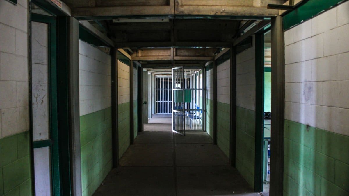 View of an empty prison corridor with open cell doors symbolizing security and isolation.