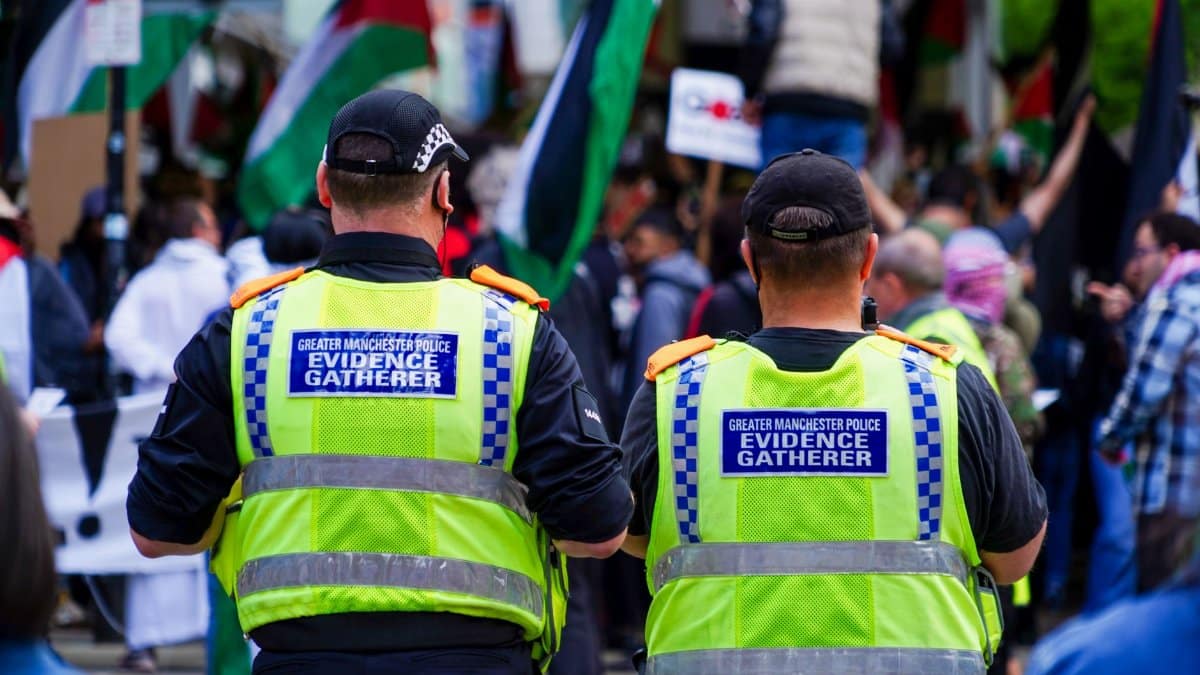 Greater Manchester Police officers gather evidence at an urban event.