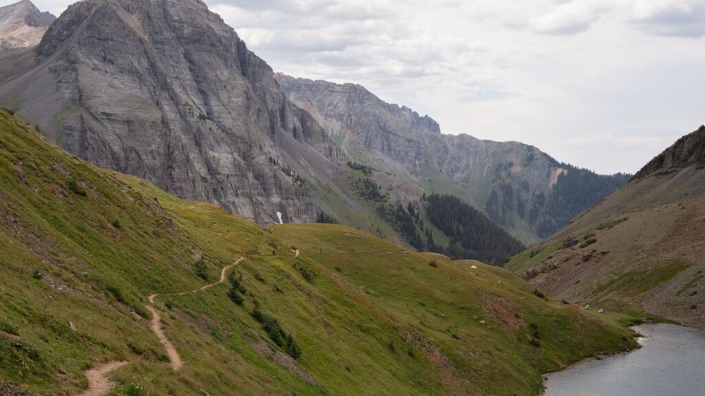 Explore the breathtaking mountain trail leading to an alpine lake in Colorado's rugged landscape.