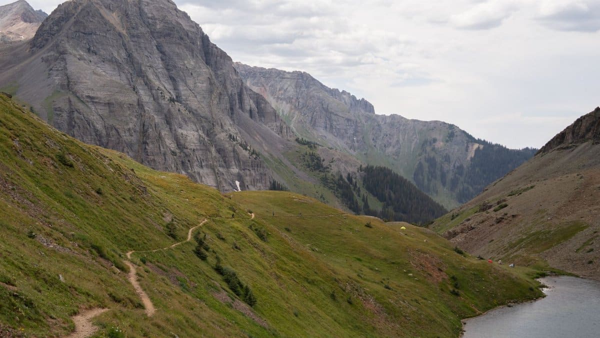 Explore the breathtaking mountain trail leading to an alpine lake in Colorado's rugged landscape.