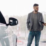 Man consulting with car salesperson in a showroom, discussing car options.