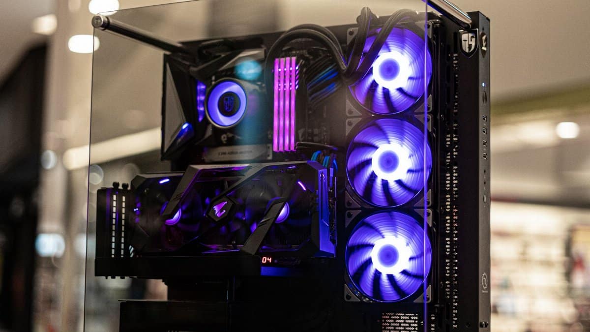 Modern gaming computer with vibrant LED fans and sleek glass design, showcasing high-performance components.