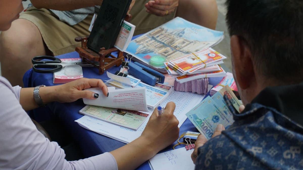 Casual gathering playing lottery outdoors in Ha Giang, Vietnam, capturing cultural street life.