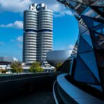 View of BMW headquarters with reflective modern architecture under a vibrant blue sky.