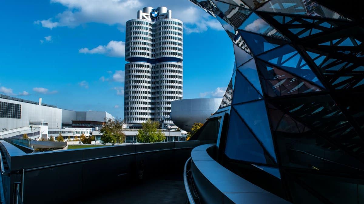 View of BMW headquarters with reflective modern architecture under a vibrant blue sky.