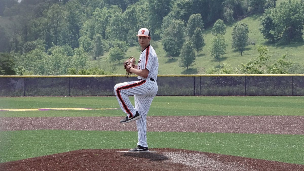 A baseball pitcher prepares to throw on a sunny day at an outdoor field.