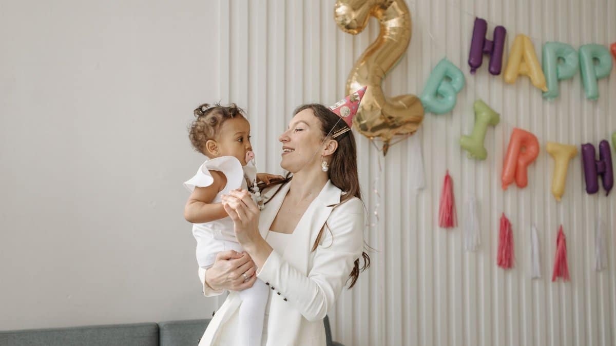 A mother and daughter enjoying a joyful birthday celebration indoors.