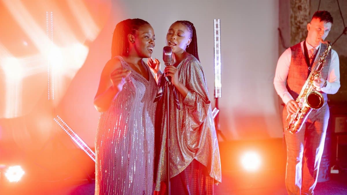 A vibrant live music performance with singers and a saxophonist under spotlights.