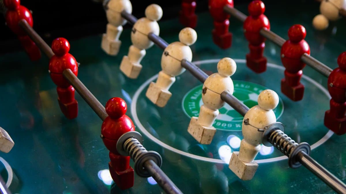 Close-up of red and white foosball players on a classic game table.
