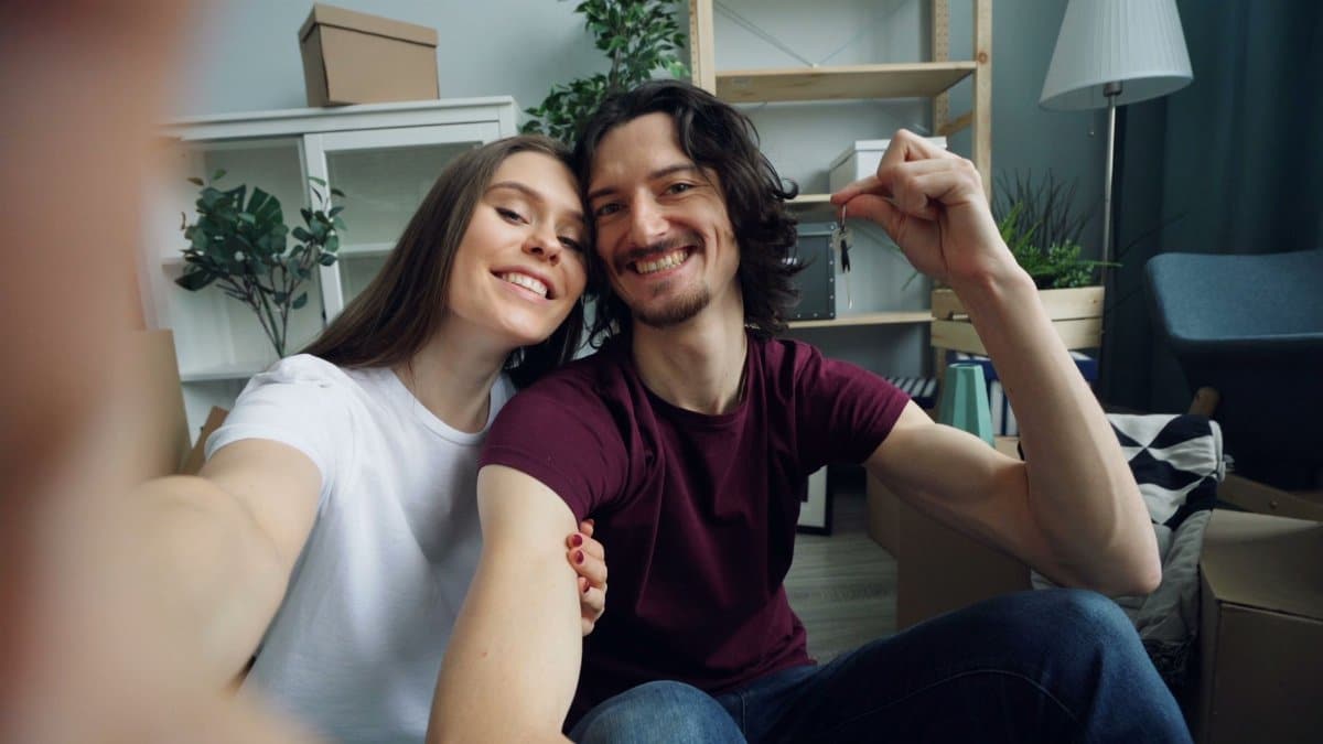 Smiling couple taking a selfie while moving into their modern apartment, displaying the excitement of a new home.