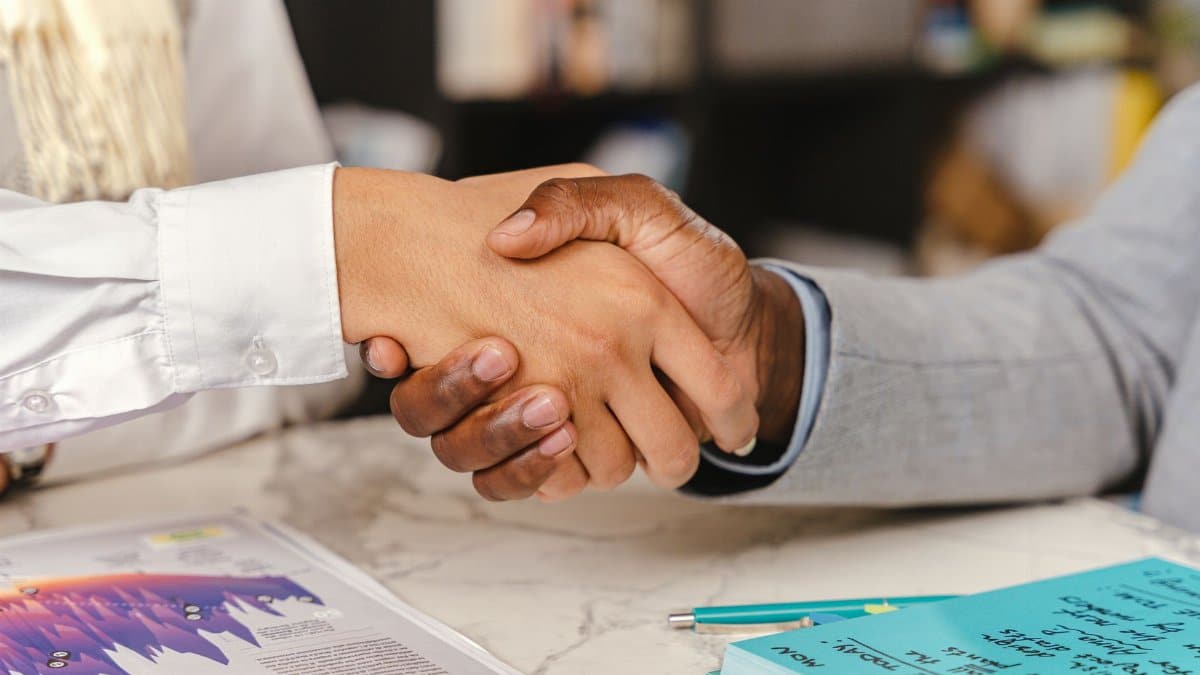 Close-up of a business handshake between two professionals over an office desk with documents.