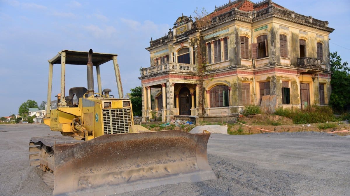 Historic building with a bulldozer outside on a construction site, under a clear sky.