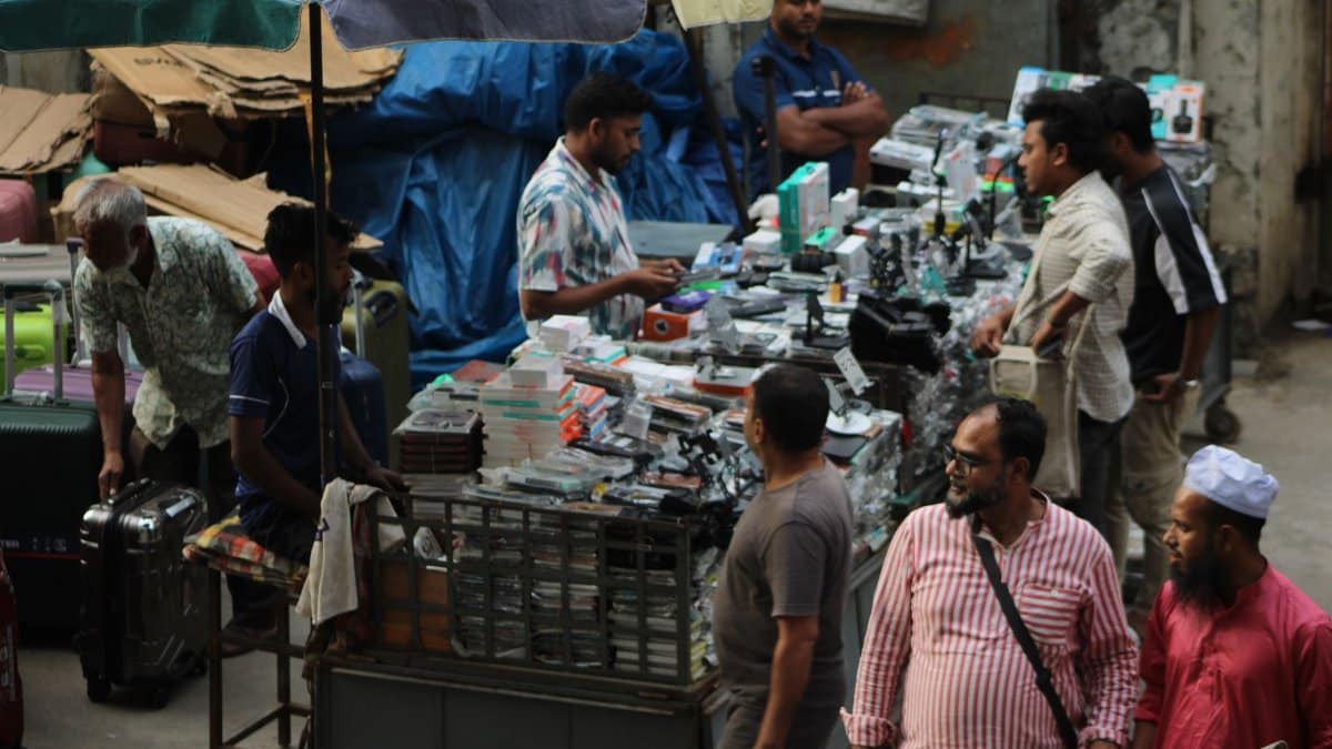 Vibrant market scene with diverse vendors selling electronics under colorful umbrellas.
