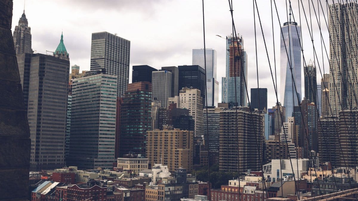 A dramatic view of the skyscrapers of New York City captured from the Brooklyn Bridge.