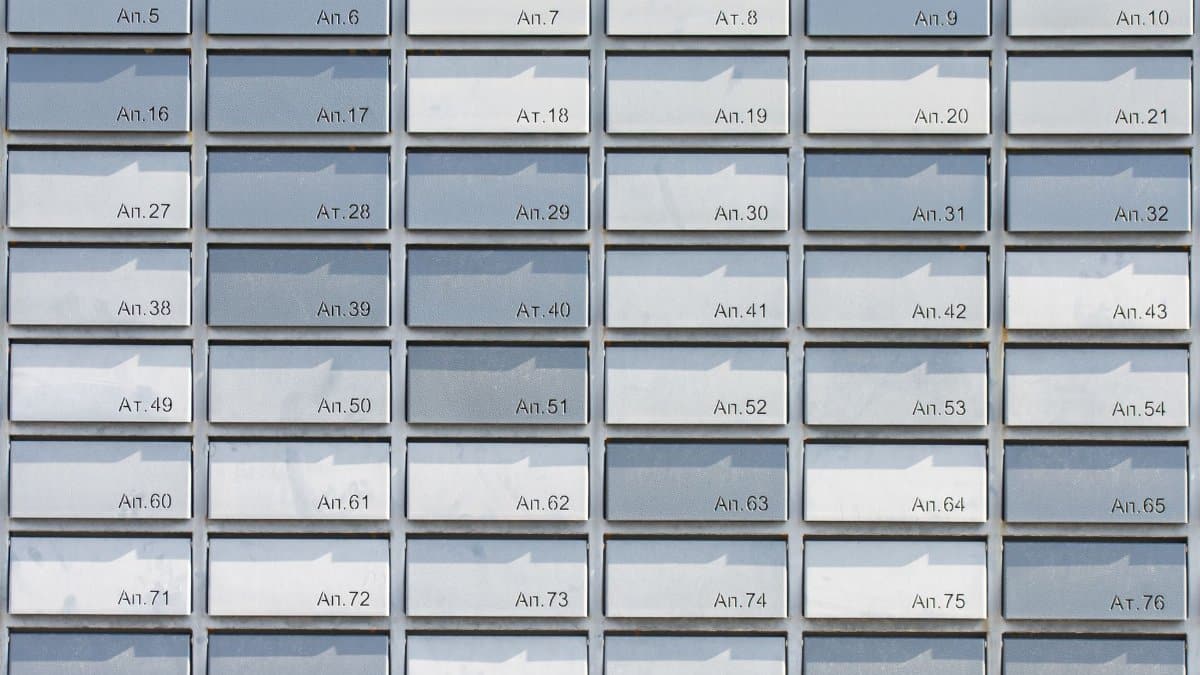 Rows of metallic apartment mailboxes organized in a neat, symmetrical grid pattern, creating a minimalist architectural design.