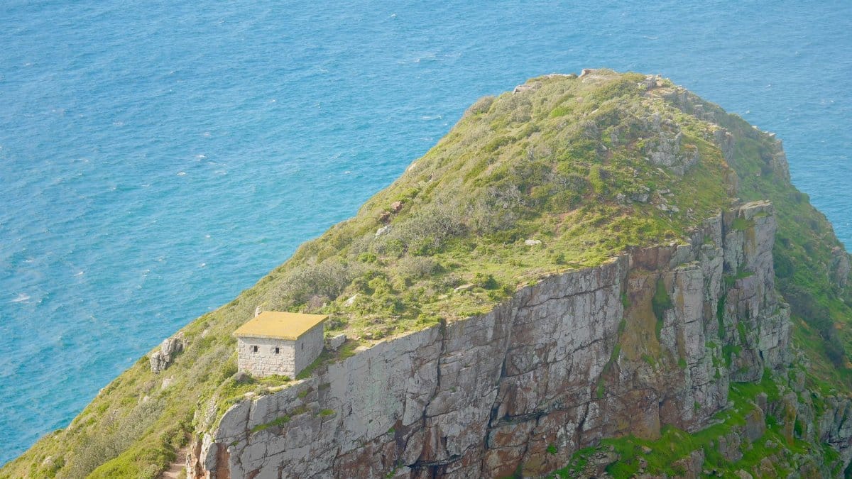 Majestic coastal cliff with isolated stone building overlooking the ocean. Perfect for nature and travel enthusiasts.