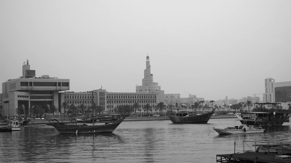 Black and white shot of Doha's harbor featuring traditional boats and the iconic spiral mosque.