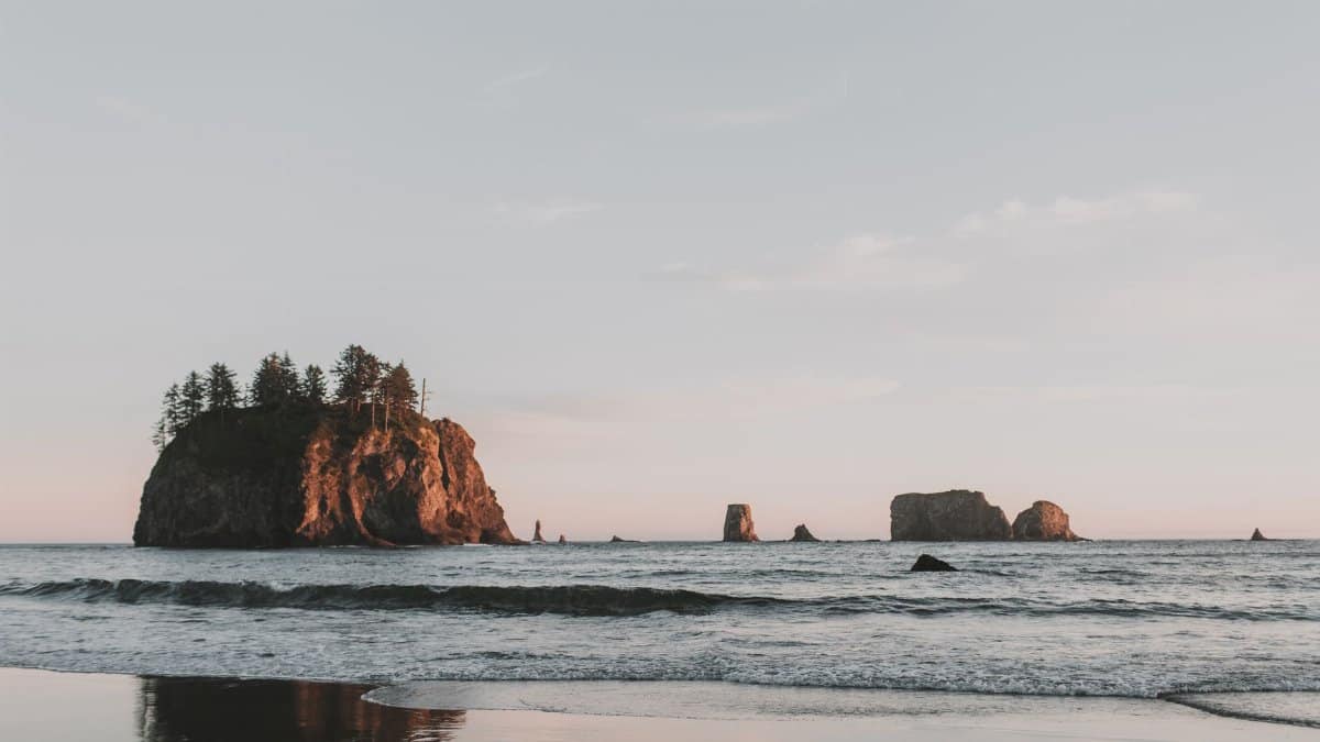 Beautiful sunset over rocky seascape with ocean waves and island formations in Washington.